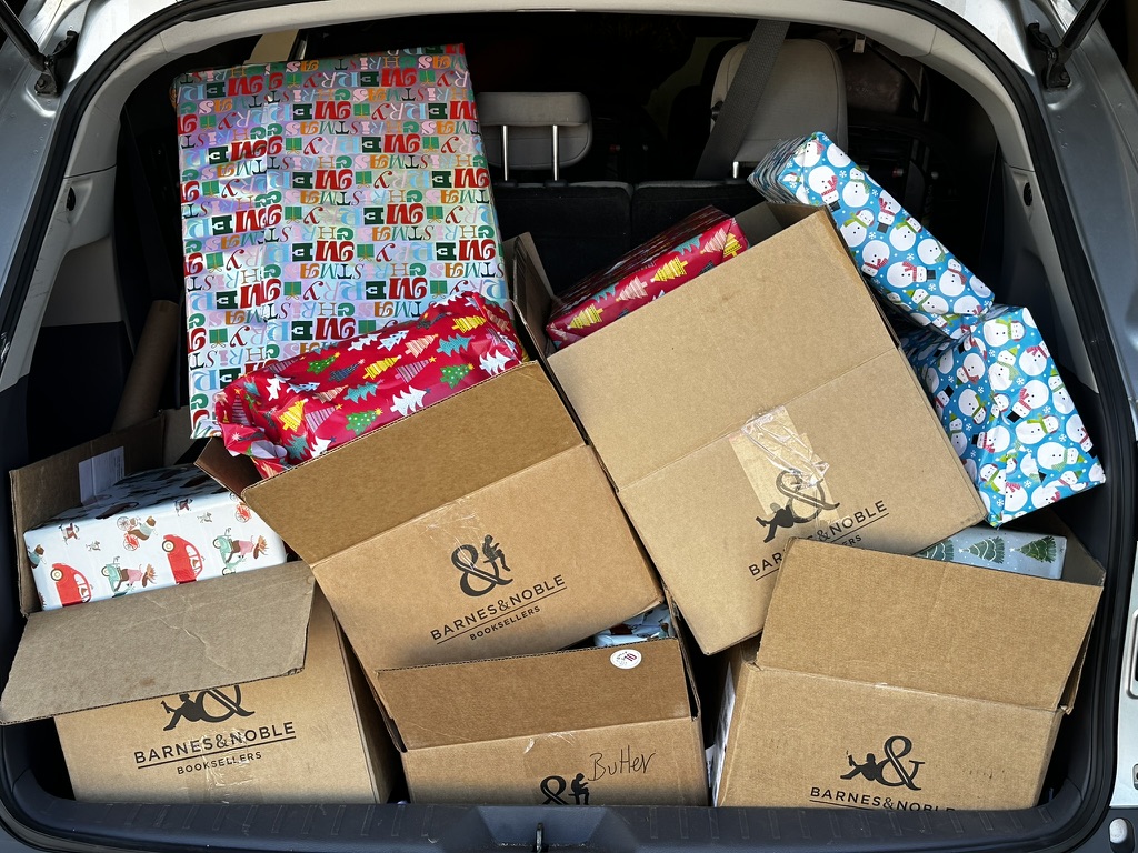 A car trunk filled with wrapped gifts and delivery boxes