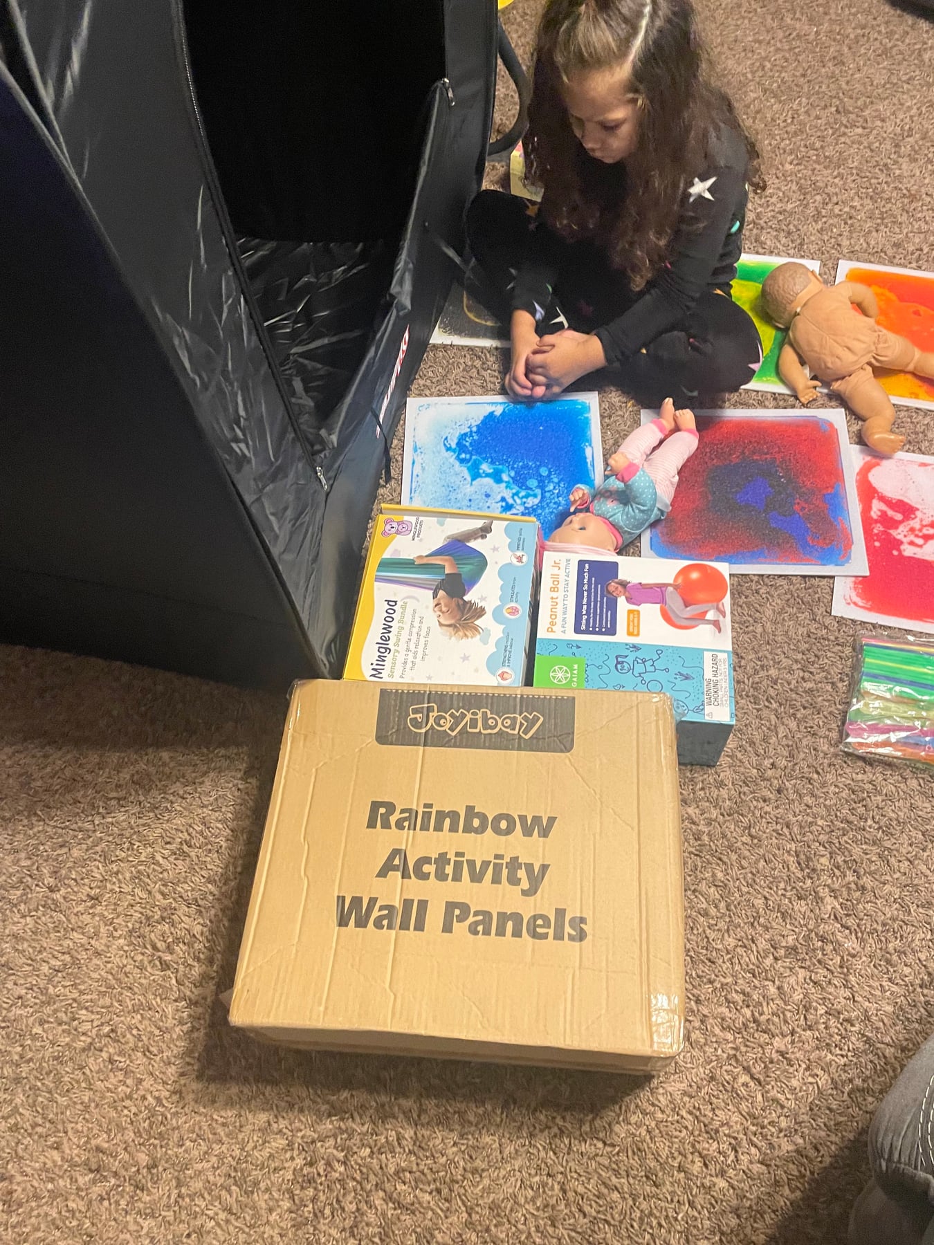 A child exploring colorful sensory wall panels after receiving gifts