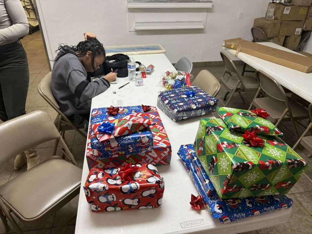 A volunteer labeling and wrapping personalized Christmas gifts