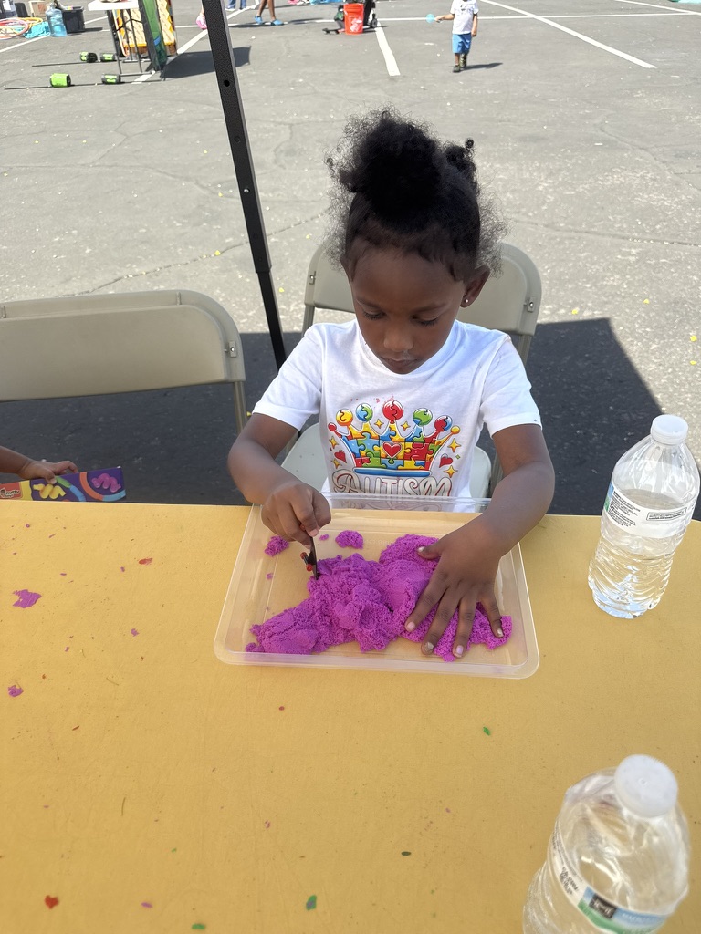 A child focused on purple sensory sand at an activity table