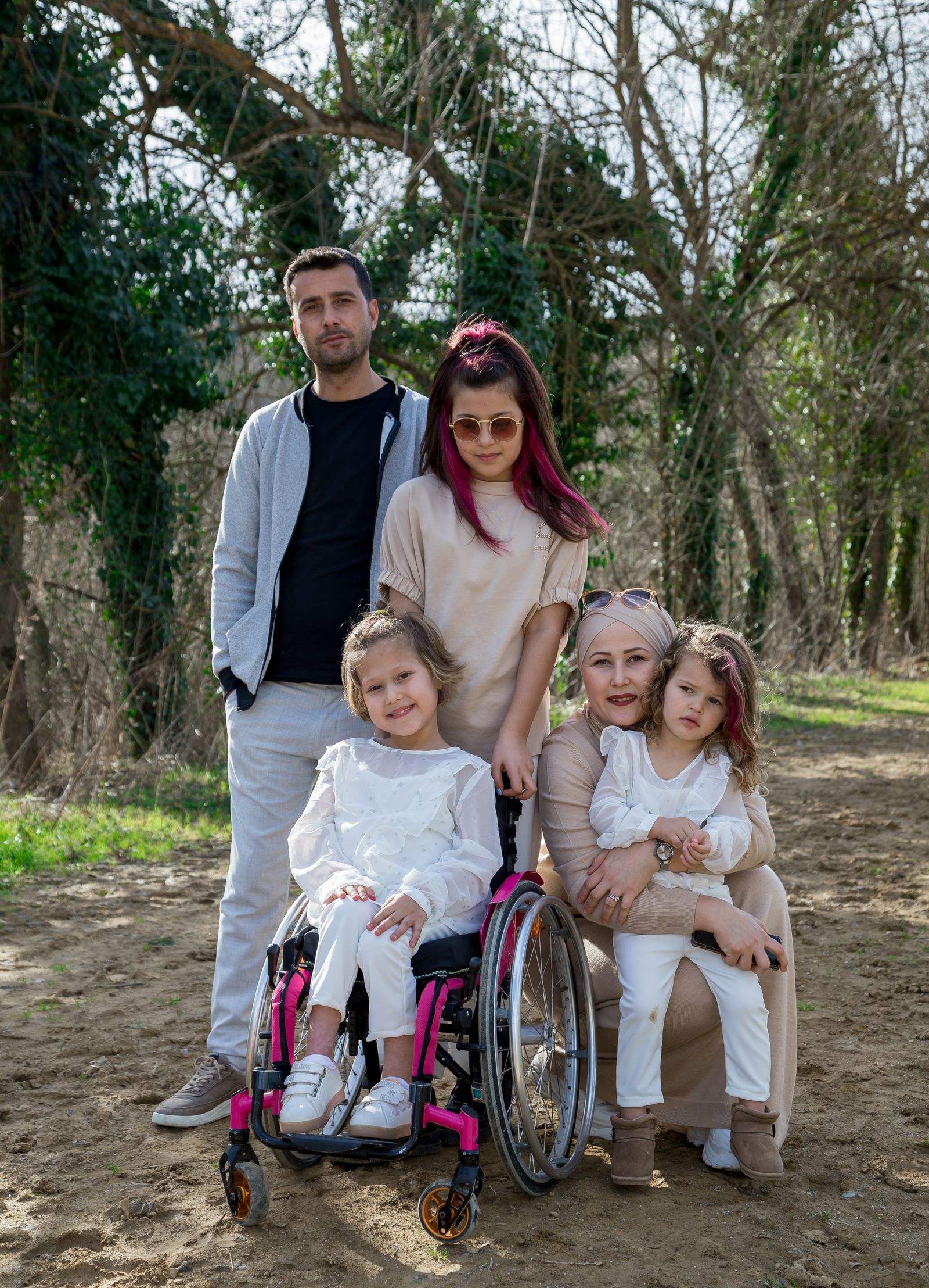 A multigenerational family outdoors with a child who uses a wheelchair