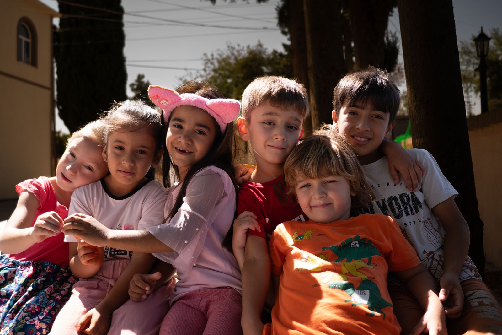 Representative image of children hugging and smiling together outdoors